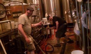 Two guys in a brewery posing for a camera