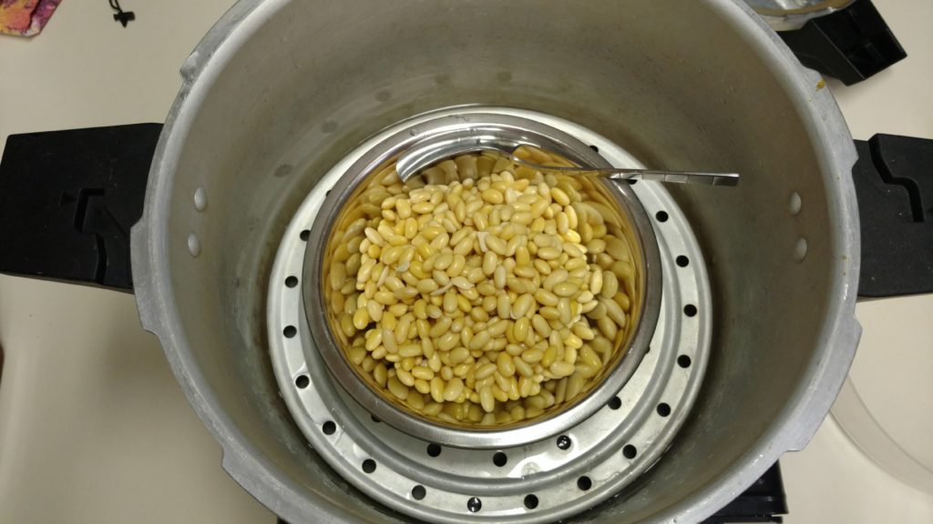 Beans in a metal bowl with metal spoon in a pressure cooker